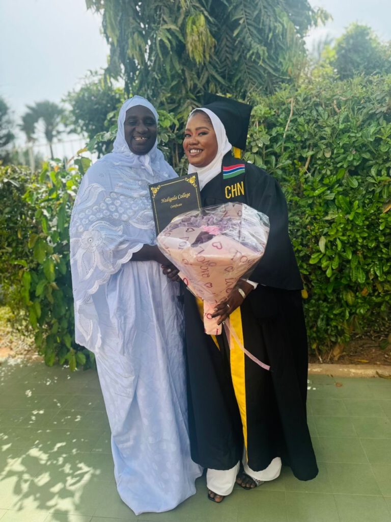 Fatou Gaye neben Adama, die Blumenstrauß und Approbation hält und schwarzen Talar trägt