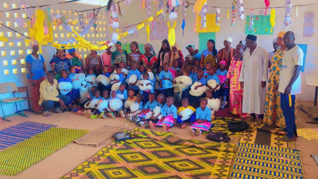 40 sitzende Kinder, Moskitonetze haltend, in Klassenraum