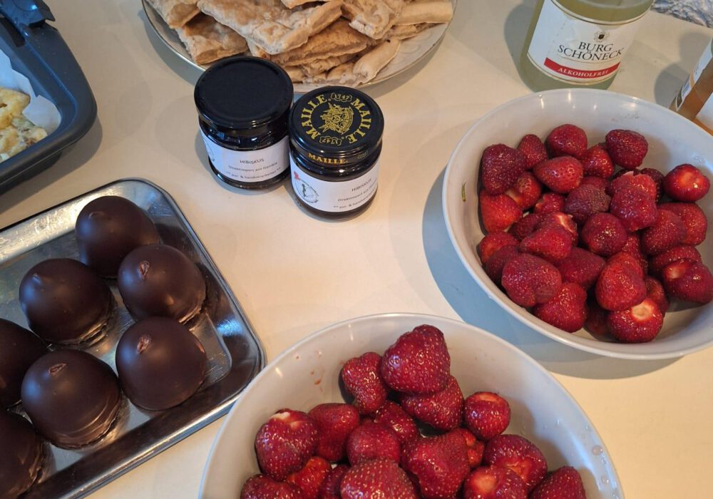 Erdbeeren in zwei Schalen, Schokoküsse, zwei Marmeladengläser und Kuchen